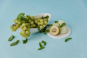 Green grapes with kiwi and mint on a blue background. photo