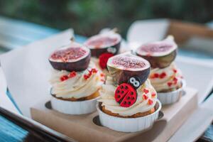 Cupcakes with figs and ladybug on wooden table. photo