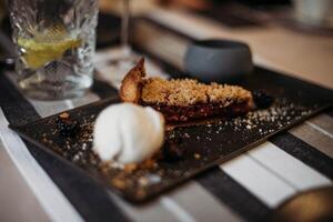 delicioso postre con hielo crema en un negro plato en un restaurante foto