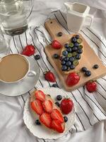 Healthy breakfast with fresh berries and coffee on wooden board, top view photo