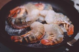 Shrimps and prawns are fried in a frying pan photo