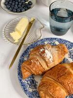 desayuno con croissants y mantequilla en un blanco mesa. foto