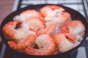 Shrimps fried in a frying pan on a gas stove. photo