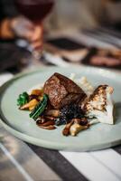 Beef tenderloin with mushrooms and spinach on a green plate photo