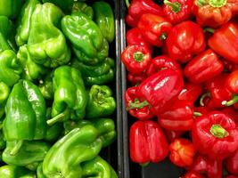 Red and green bell peppers on the counter of the store. Background photo