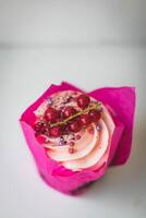cupcake with red currant and pink cream on a white background photo