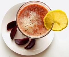 Glass of beetroot smoothie with lemon on a white background. photo