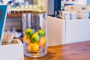 Citrus fruits in a glass vase on a wooden table photo