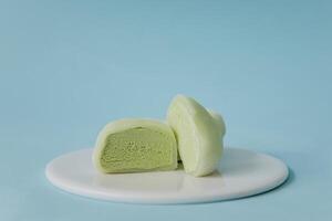 Green tea mochi on a white plate on a blue background photo