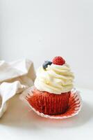 Red velvet cupcake with fresh raspberries and blueberries on white background photo