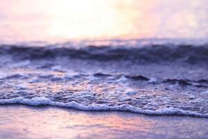 suave ola de el mar en el arenoso playa a puesta de sol tiempo. foto