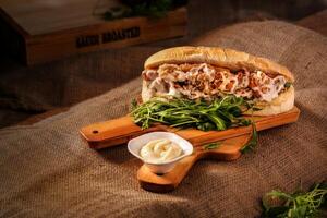 Sandwich with chicken, cheese and arugula on wooden board photo