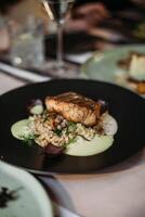 Tasty salmon fillet with risotto on a black plate. photo