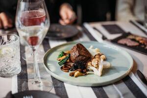 Beef steak with mushrooms and black caviar on a green plate photo