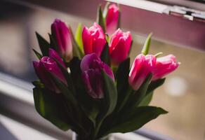 Bouquet of pink tulips in a vase on the windowsill photo