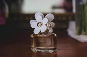 Bottle of perfume with flower on the table. Selective focus. photo