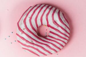 Donut with pink icing and pink sprinkles on a pink background photo