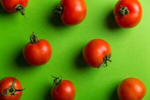 Ripe red tomatoes on a green background. Flat lay, top view photo
