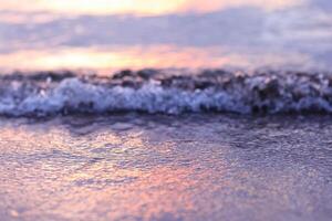 suave ola de el mar en el arenoso playa a puesta de sol. selectivo enfocar. foto