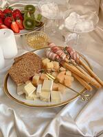 Cheese platter with fruits and bread on a white tablecloth photo