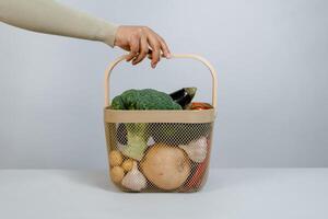 mujer mano participación un cesta lleno de Fresco orgánico vegetales. cero residuos concepto. foto