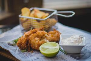 Crispy fried fish and chips with mayonnaise and lime photo