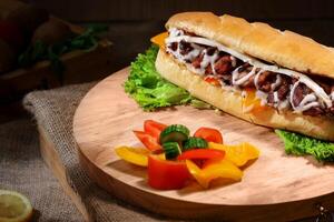 caliente perro con carne y vegetales en un de madera tablero en un oscuro antecedentes foto