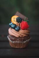 Chocolate cupcake with fresh berries and chocolate bar on dark background photo