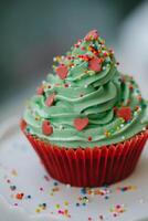 Cupcake with green frosting and colorful sprinkles on top photo