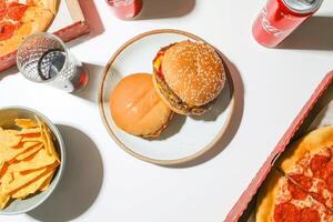 Overhead view of hamburger with chips and soda on white table photo