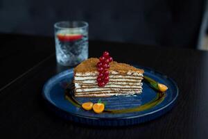 Tiramisu cake with red currant on a blue plate photo