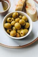 Green olives in a bowl with bread and cup of tea. photo