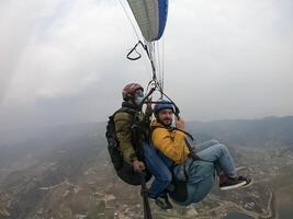 parapente en el montañas, el dos personas en el parte superior de el montaña, el paracaidistas son volador con un paracaídas foto