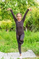 pretty girl doing yoga exercises, little girl doing yoga exercises in the garden photo