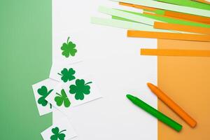 Irish flag made from color paper with cut out shamrock clover and crayons photo