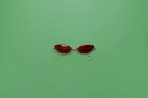 Orange sunglasses on green background photo