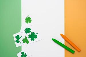 Irish flag made from color paper with cut out shamrock clover and crayons photo