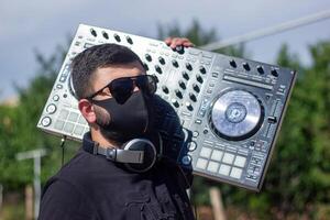 DJ con auriculares y mezclador en el parque, el DJ a trabajo foto