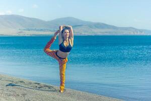 perrson doing yoga exercise on the beach, person relaxing on the beach, personn doing yoga photo