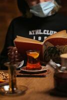 Person Wearing Face Mask Reading Book Indoors photo