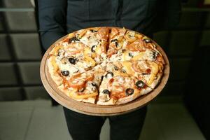 Person Holding a Pizza With Olives photo
