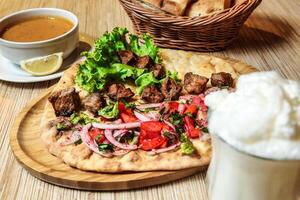 Pita With Meat, Vegetables, and Sauce Next to a Cup of Coffee photo