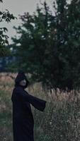 Field with ghost in countryside. Spooky field with ghost in black cloak Vertical video