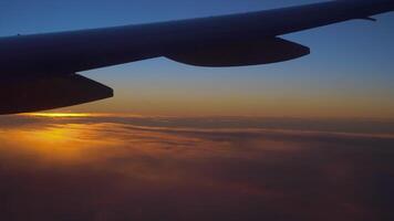 ver desde el avión ventana de el ala, nubes y un hermosa puesta de sol. video