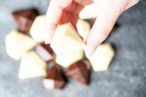 Hand Picking up a Piece of Chocolate on a White Plate photo