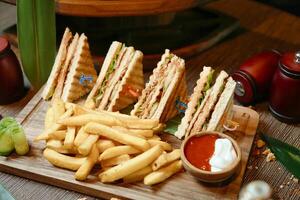 de madera corte tablero con medio emparedado y francés papas fritas foto