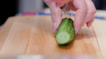 senior Kaukasisch vrouw besnoeiing een groen komkommer Aan houten snijdend bord video