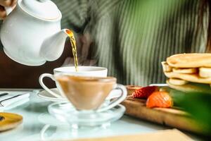 Person Pouring Tea Into Cup on Table photo