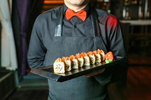 Man in Apron Holding Tray of Sushi photo