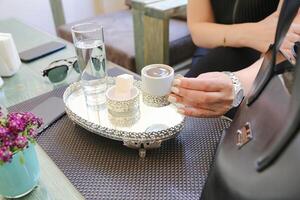 Woman Holding Cup on Tray at Table photo